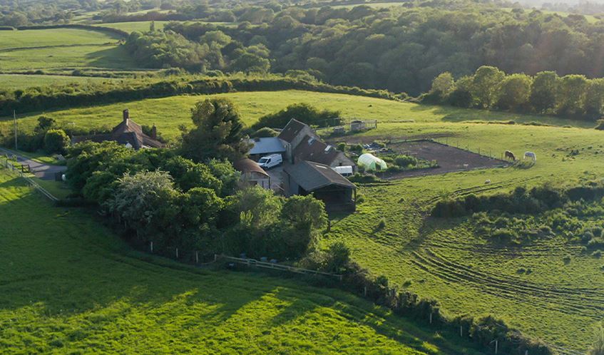 A farm sits among fields in the English countryside.