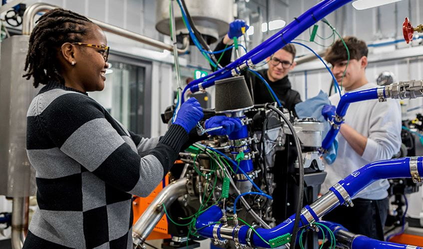 Three young people stood working with technical engineering equipment in a studio
