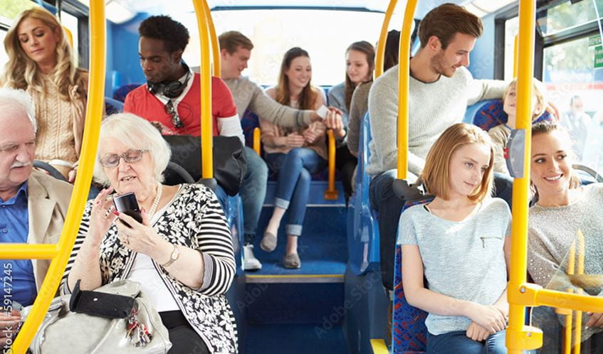 A bus is full with passengers as it travels along.