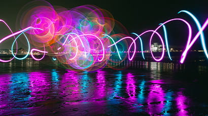 A colourful display of twirling lights above water.