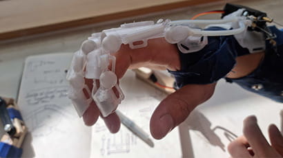 A close up picture shows an exoskeletal bionic glove covering a hand.