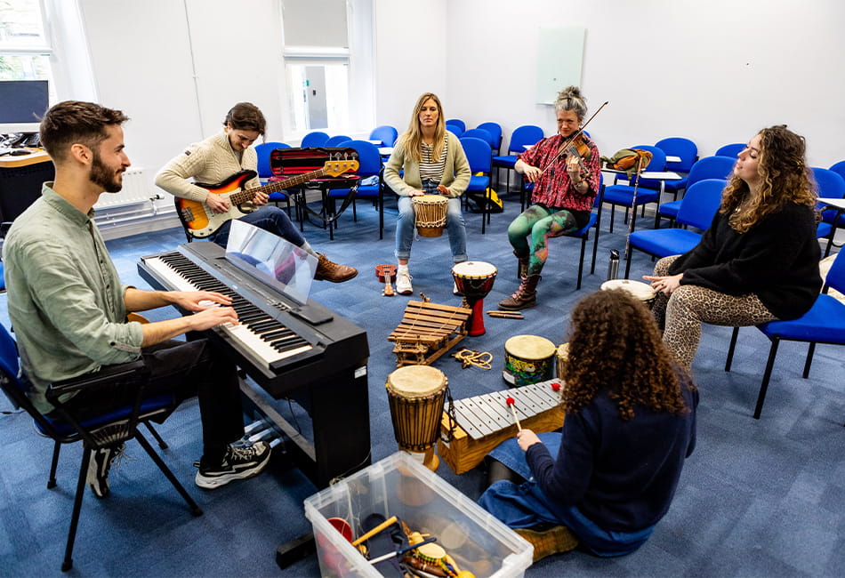 Group of students playing a variety of musical instruments together.