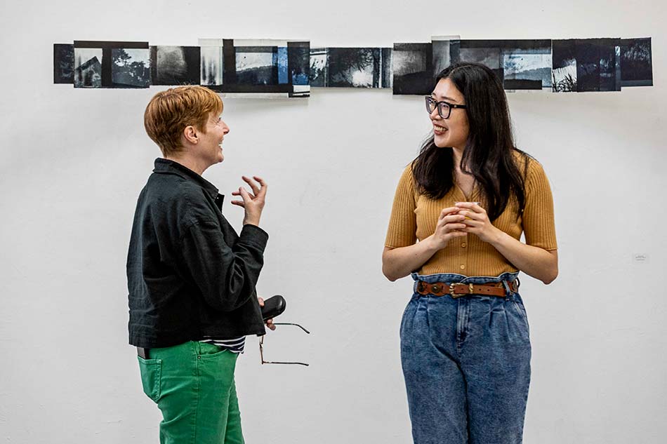 Student talking with lecturer at art exhibition