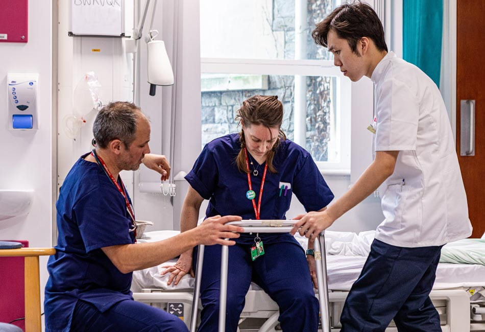 A physiotherapy student supporting a patient with physical exercises.