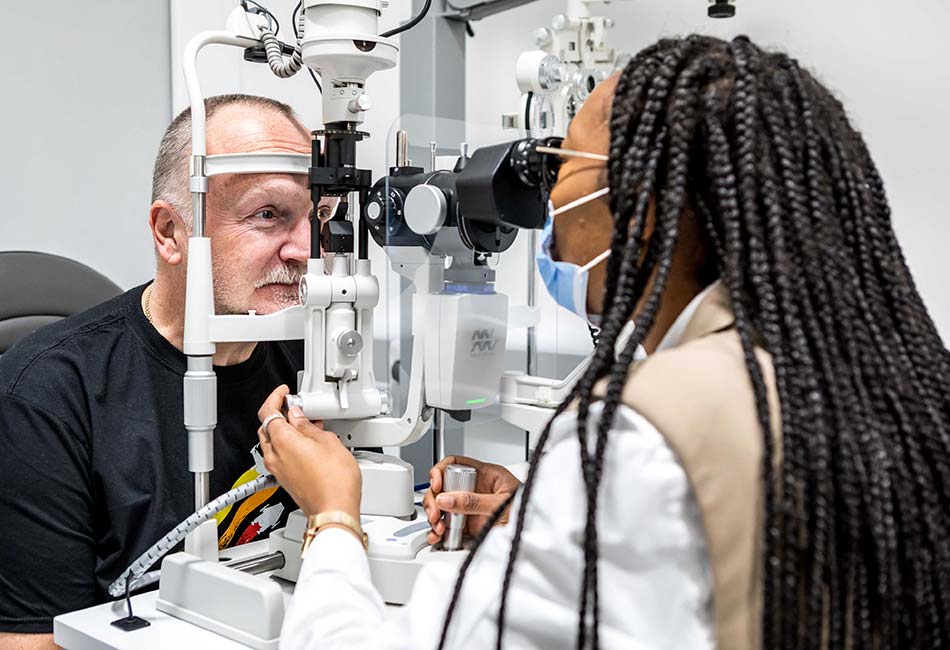 Optometrist using equipment to look into the eye of a patient