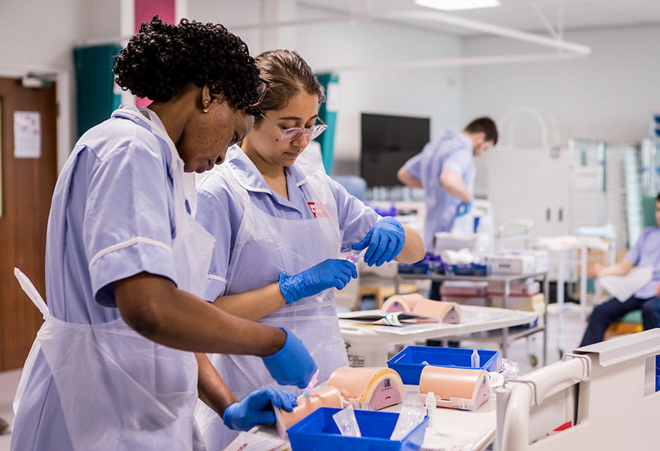 Nursing students practising their skills in a classroom.