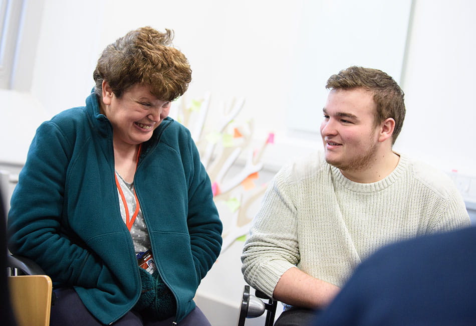 Two people talking and smiling at each other.