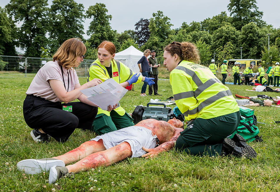 Two paramedic students helping an injured person during a simulation exercise with their instructor.