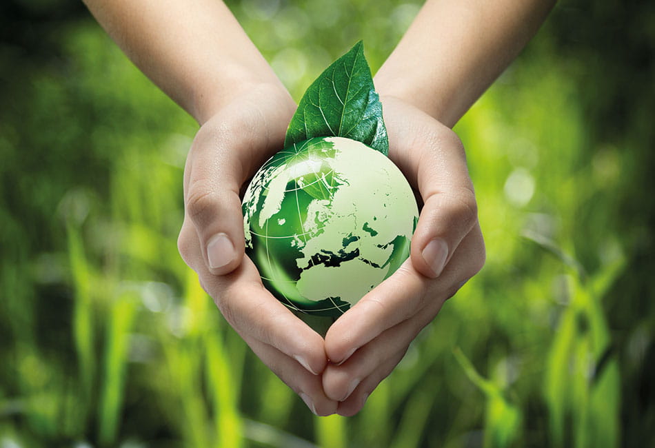 Human hands holding a small green earth globe.