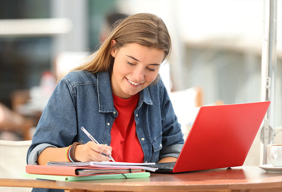 A student studying with a red laptop.