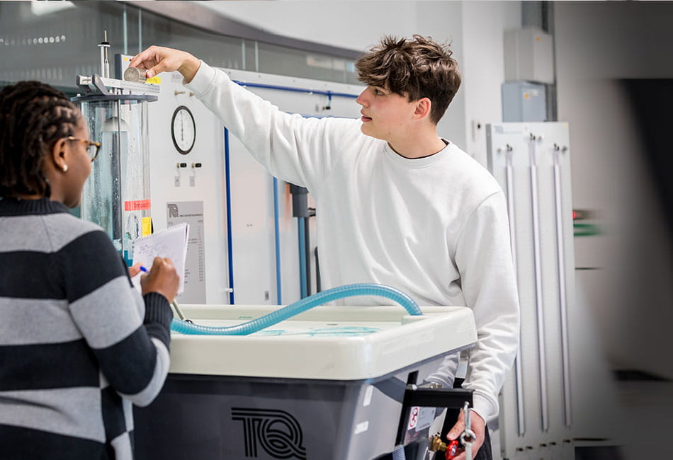 Two students completing tests on a machine.