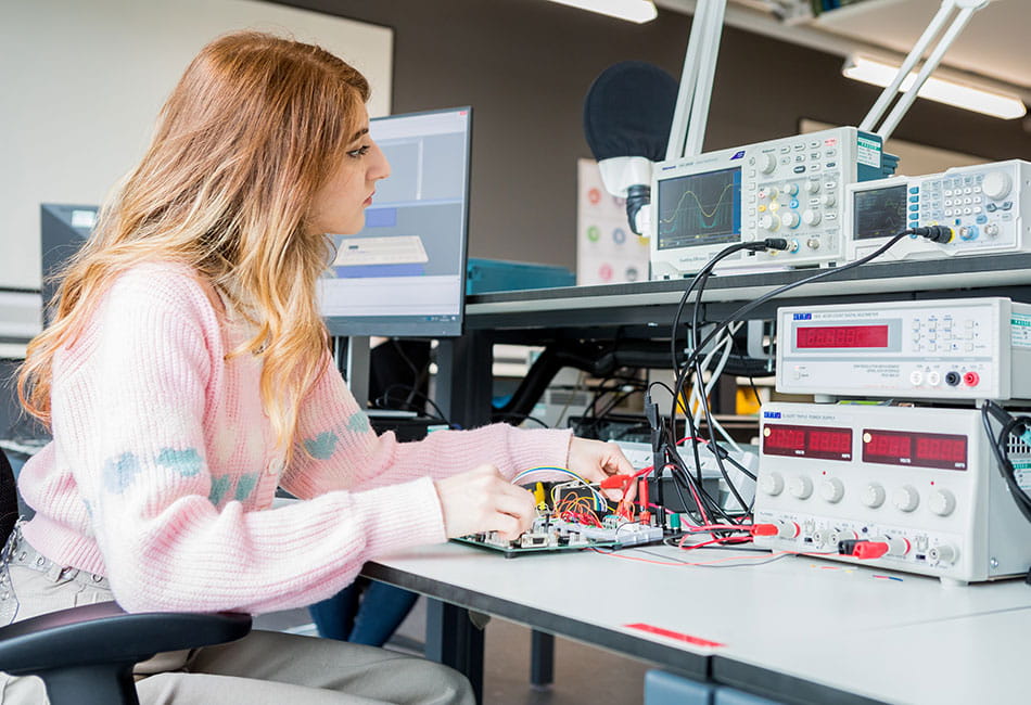 A student testing an electronic circuit board.