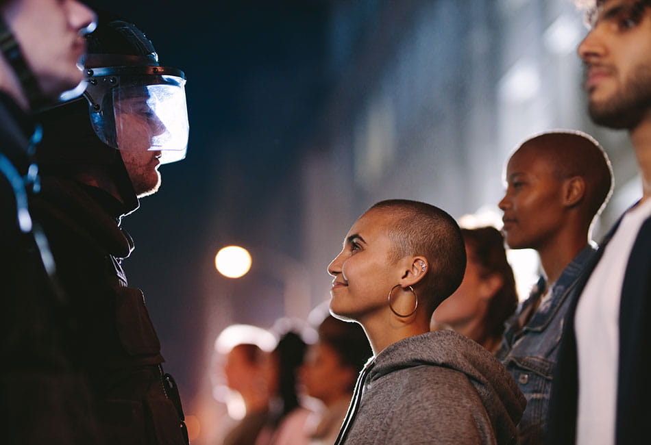 A row of people standing in front of police officers.