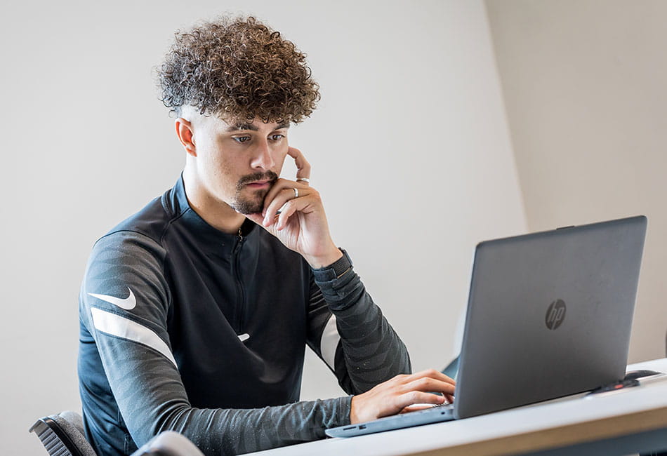 A student studying on their laptop with a focused expression.