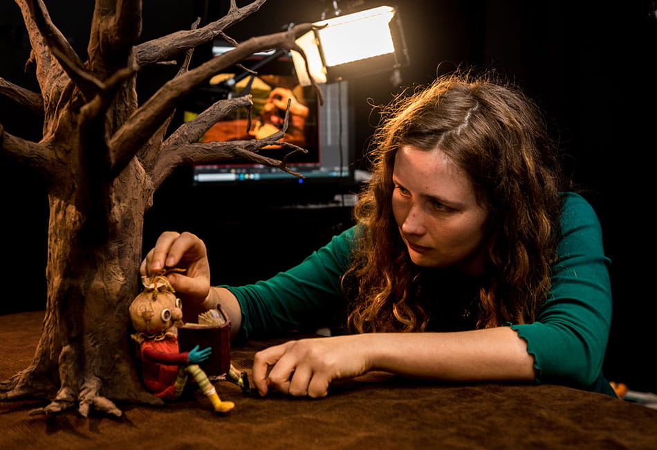 A student setting up a clay figure ready for animation filming using stop-motion technique.