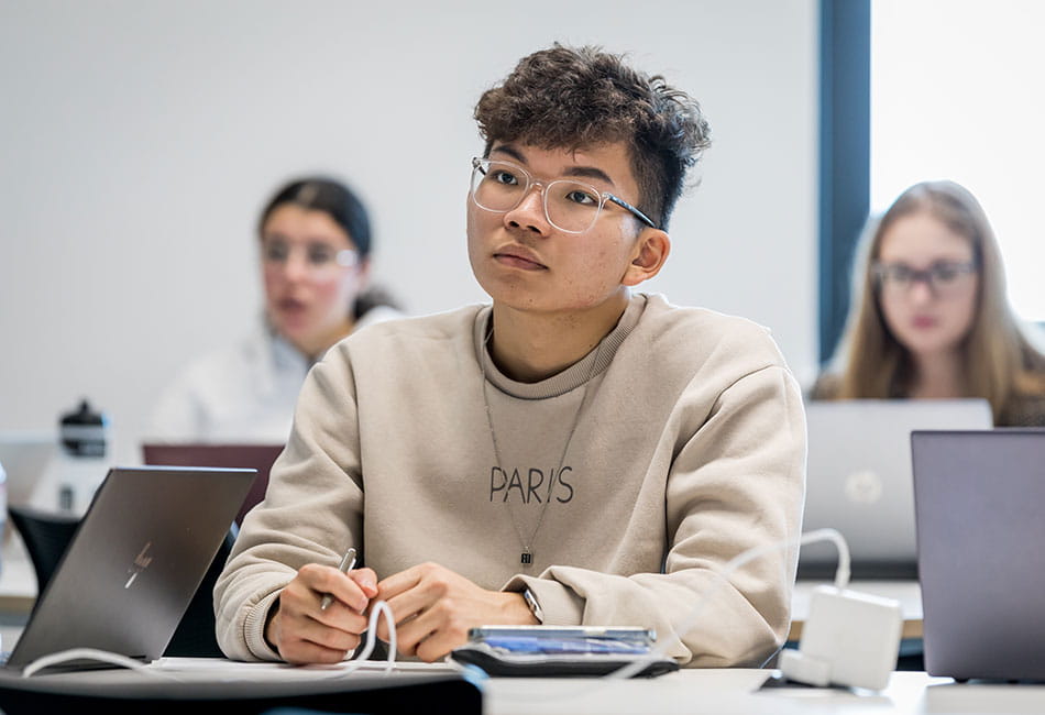 Some students studying in a classroom with their laptops.