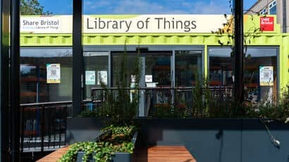 A picture of the Library of Things, which is in a green shipping container and has tables with plants on outside it.
