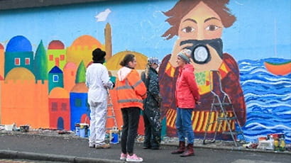 Group stood in front of colourful mural in Stokes Croft Bristol.