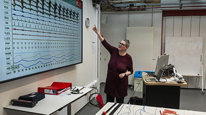 Lecturer talking through a chart displayed on large screen.