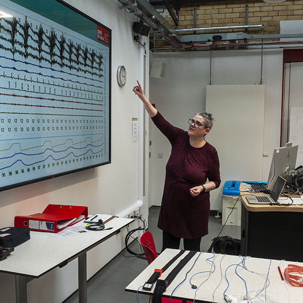 Lecturer talking through a chart on a large screen.