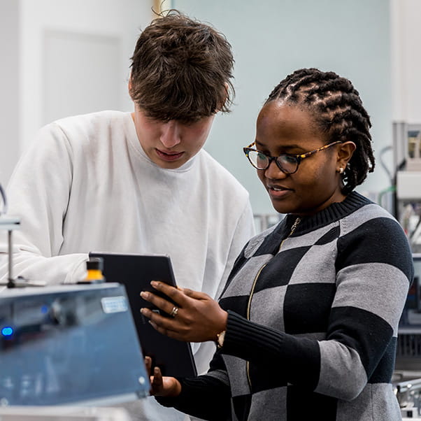 Two students in an engineering lab looking at a tablet screen together.