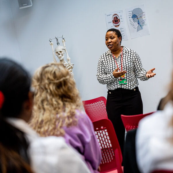 A healthcare professional giving a talk to university students.