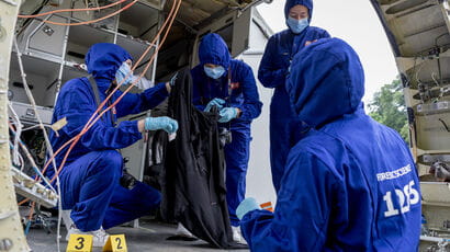 Four Forensic Science students in overalls taking part in a simulated accident.