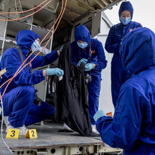 Four Forensic Science students in overalls taking part in a simulated accident.