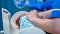 Close-up of a nurse gently caring for a newborn baby in a maternity unit.