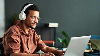Man sitting at a laptop with headphones on.