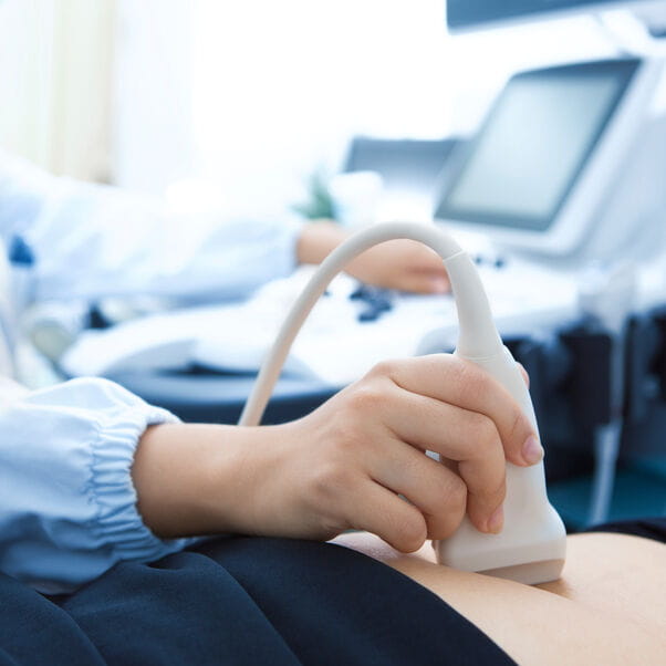 Sonographer using an ultrasound machine to assess a patients tummy.