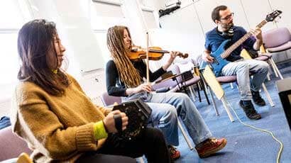 Some students playing musical instruments in a classroom.