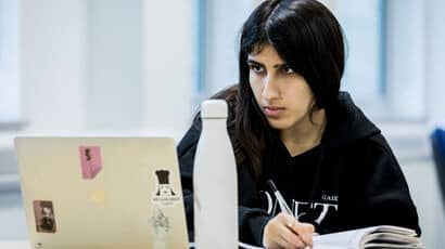 Person looking at their laptop and making notes.