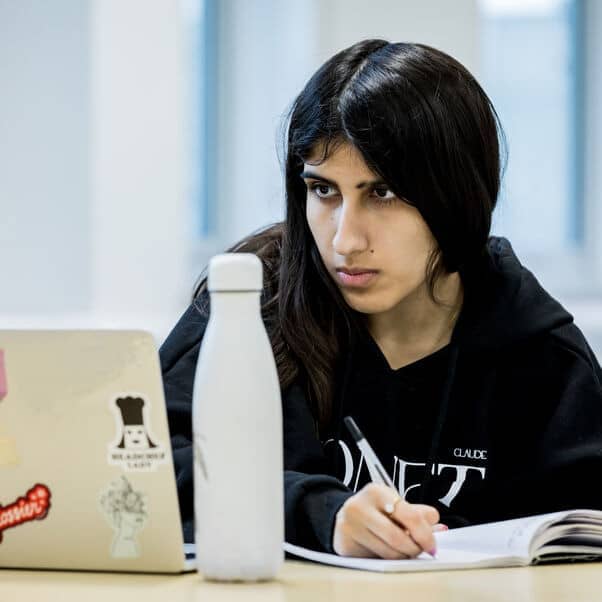A person making notes whilst looking at her laptop