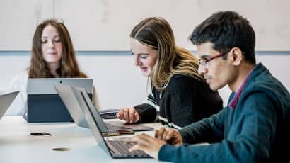 Three marketing students working at laptops.