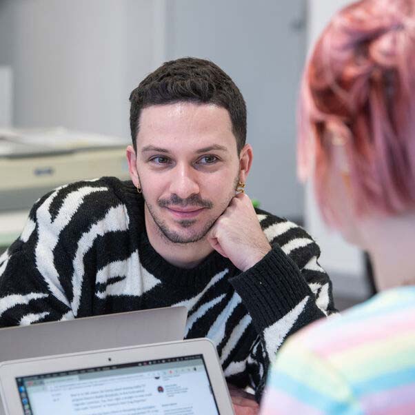 Person smiling over a desk at an adviser.