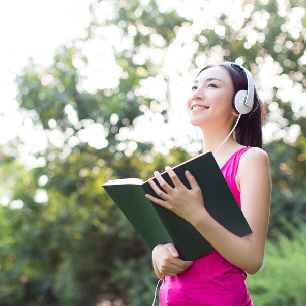 Girl smiling outside holding a book in the fitness outfit.