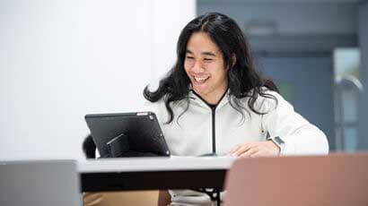 Smiling man sat looking at a tablet.