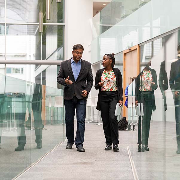 A couple of academics chatting whilst walking on a walkway.