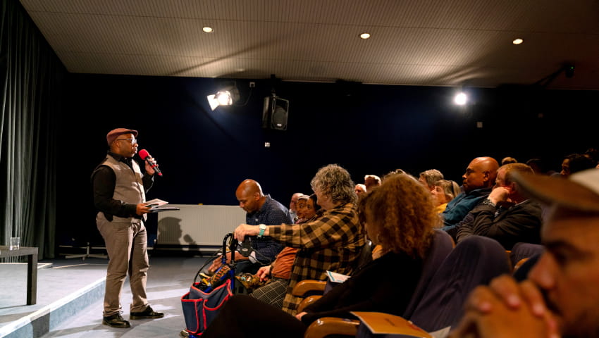 Speaker at BDAS event standing in front of a crowd, giving a speech with a handheld microphone.