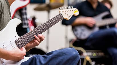 Someone attending a music lesson and playing an electric guitar.