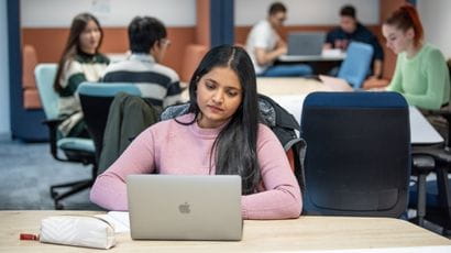 Student working on a laptop in a study space at Frenchay Campus