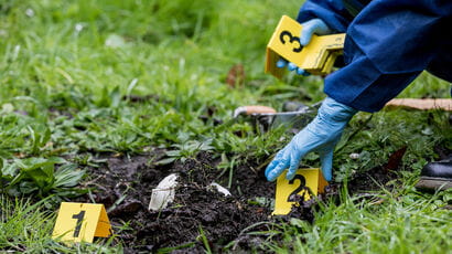 A forensic science student laying out coloured labels on the ground to indicate evidence.