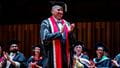 Professor Steve West clapping on stage at the graduation ceremony