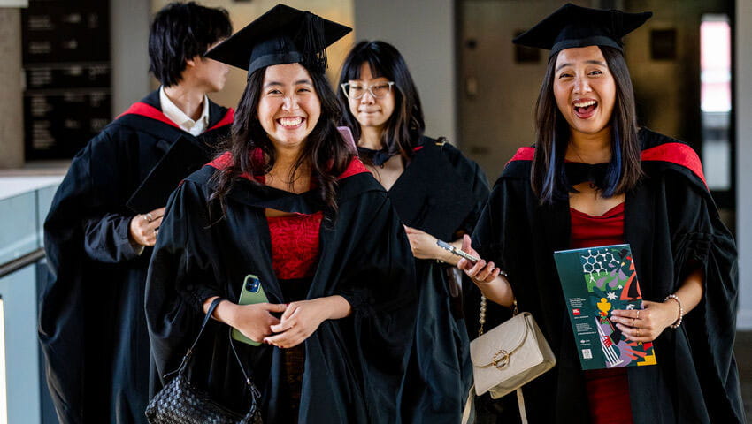 A group of graduates in robes smiling.