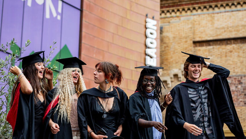 A line of graduates in robes outside the Bristol Beacon.