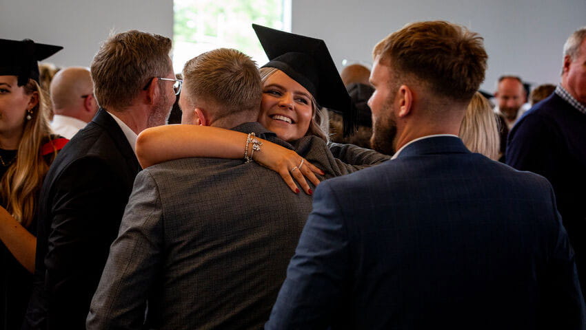 Smiling graduate hugging a family member