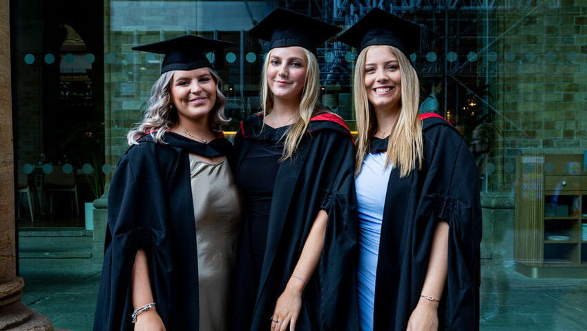 Three graduates smiling at the camera.