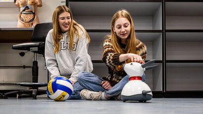 Two students running a practical scenario with a smart robot dog.