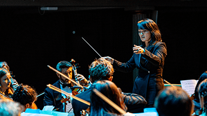 Woman in black conducting an orchestra